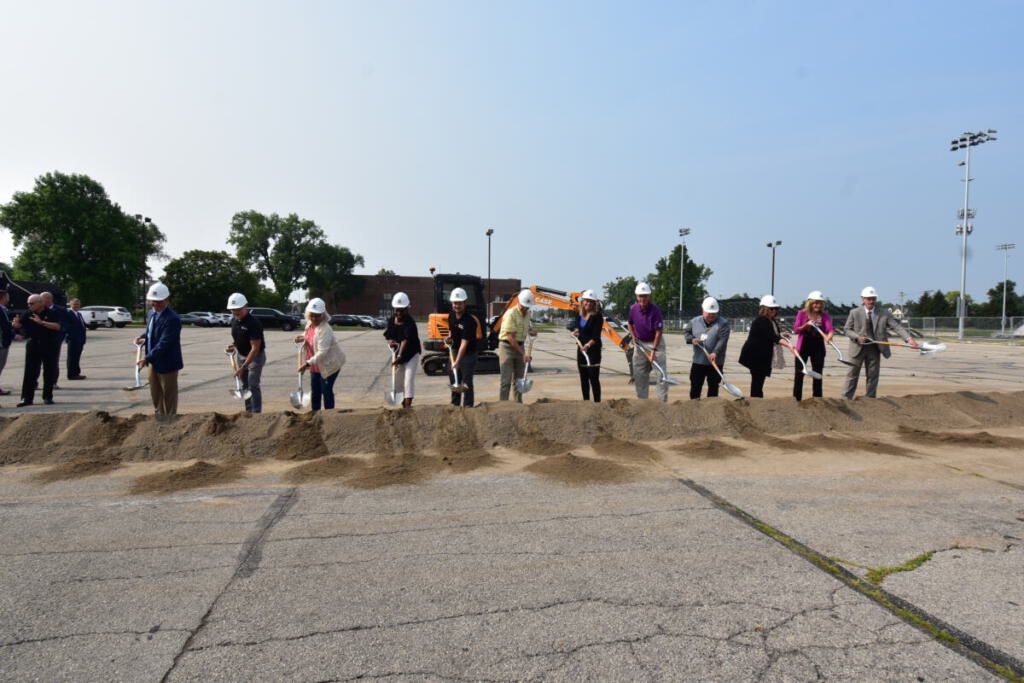 Attendees posing with Weigand hardhats and shovels at the groundbreaking site.